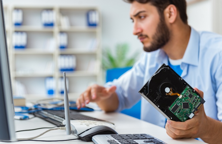 Computer tech holding a hard drive while working on a computer