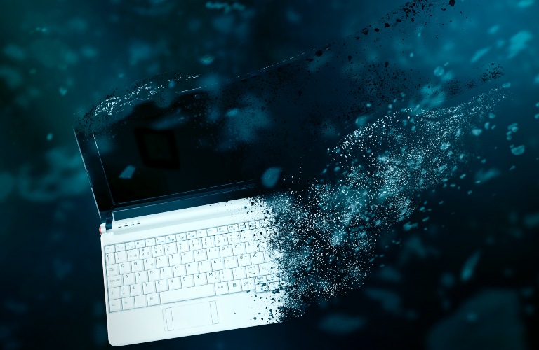 Laptop computer disintegrating on blue background