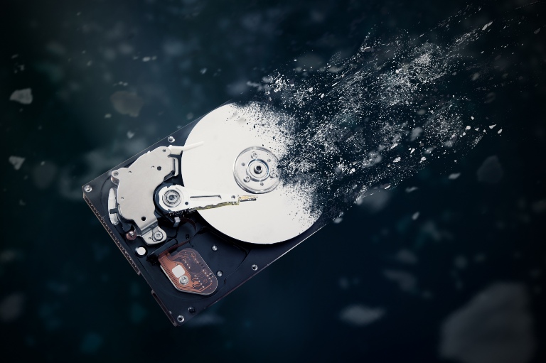 Hard drive disintegrating into space on black background