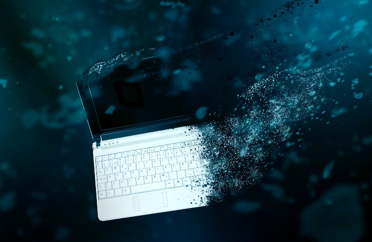 Laptop disintegrating on a blue background