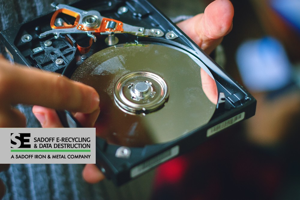 Man pointing to a hard drive platter with the Sadoff logo