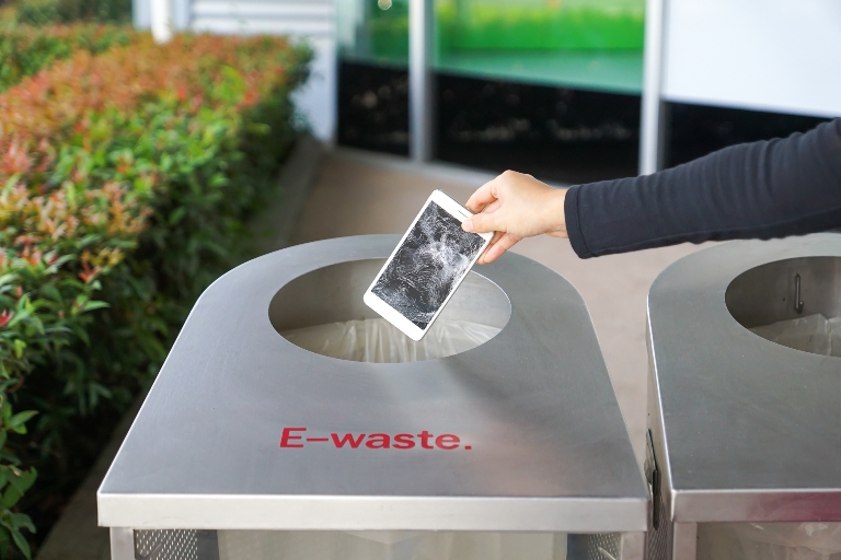 person throwing phone into e-waste recepticle