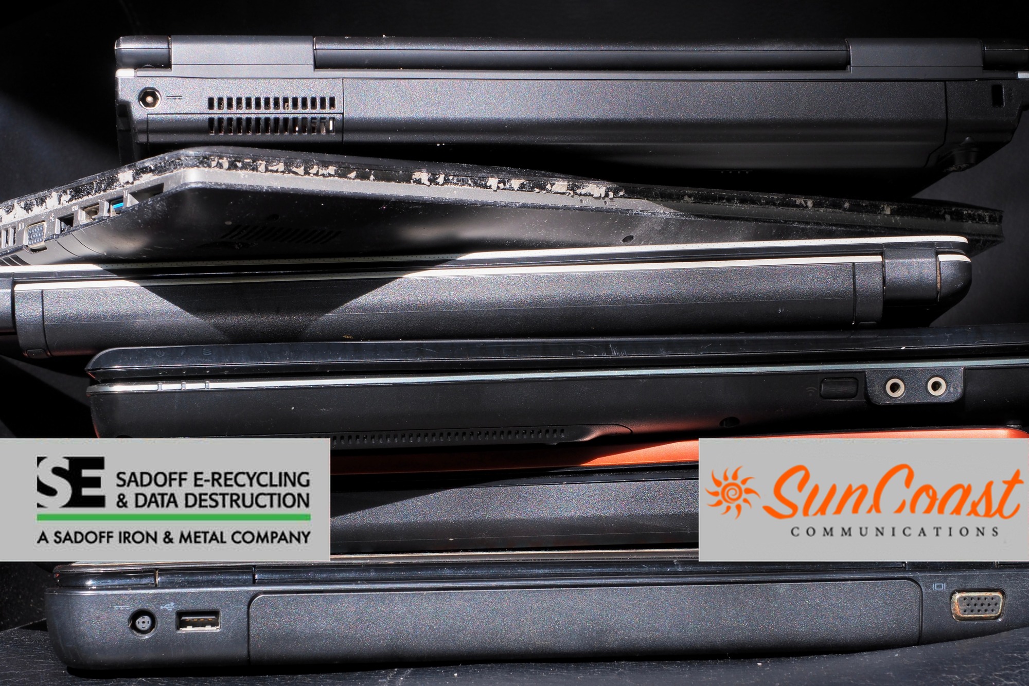 Stack of broken laptops with Sadoff and SunCoast logos